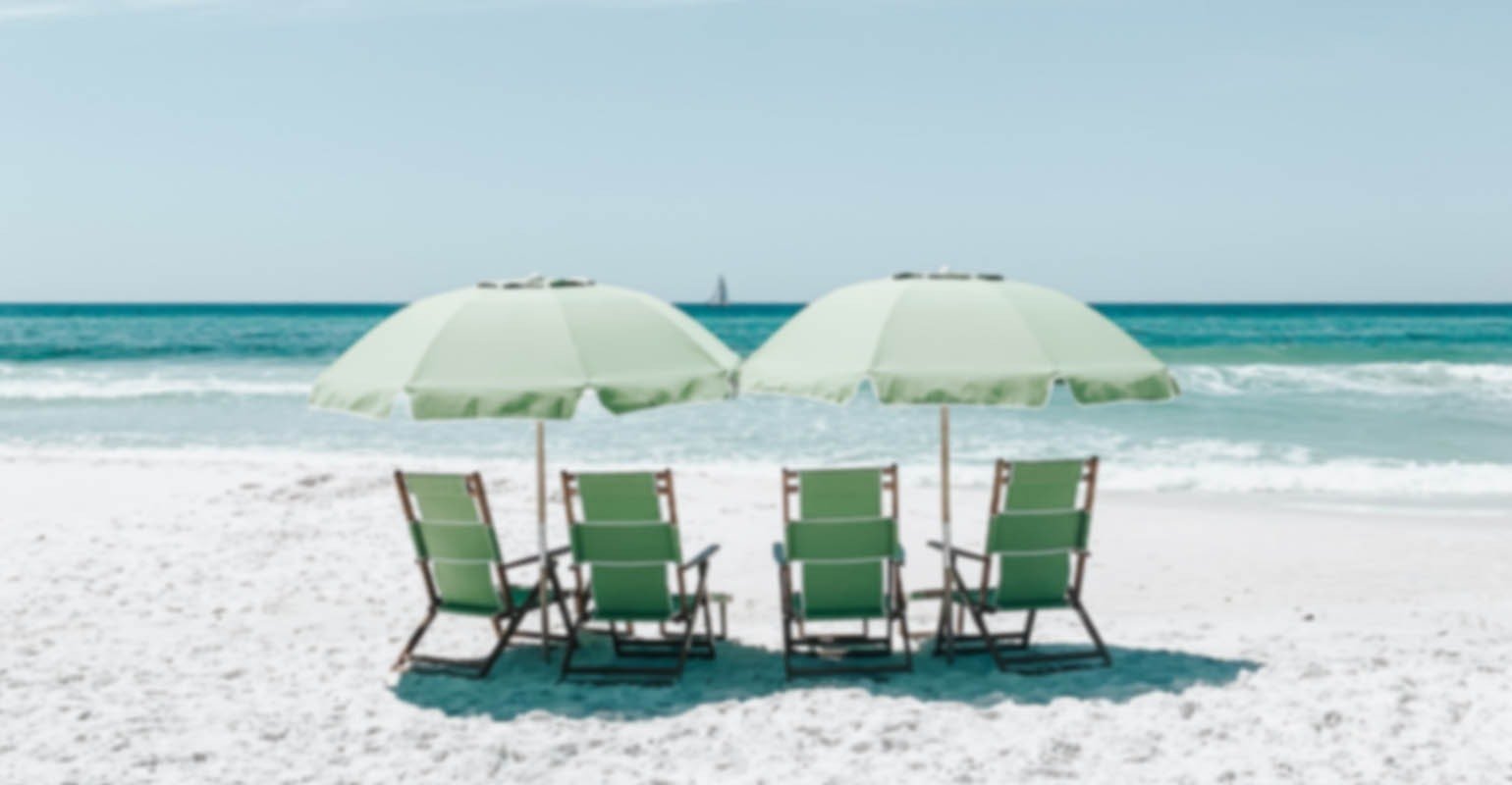 Une image floue de chaises vertes sous des parasols sur le sable de la plage